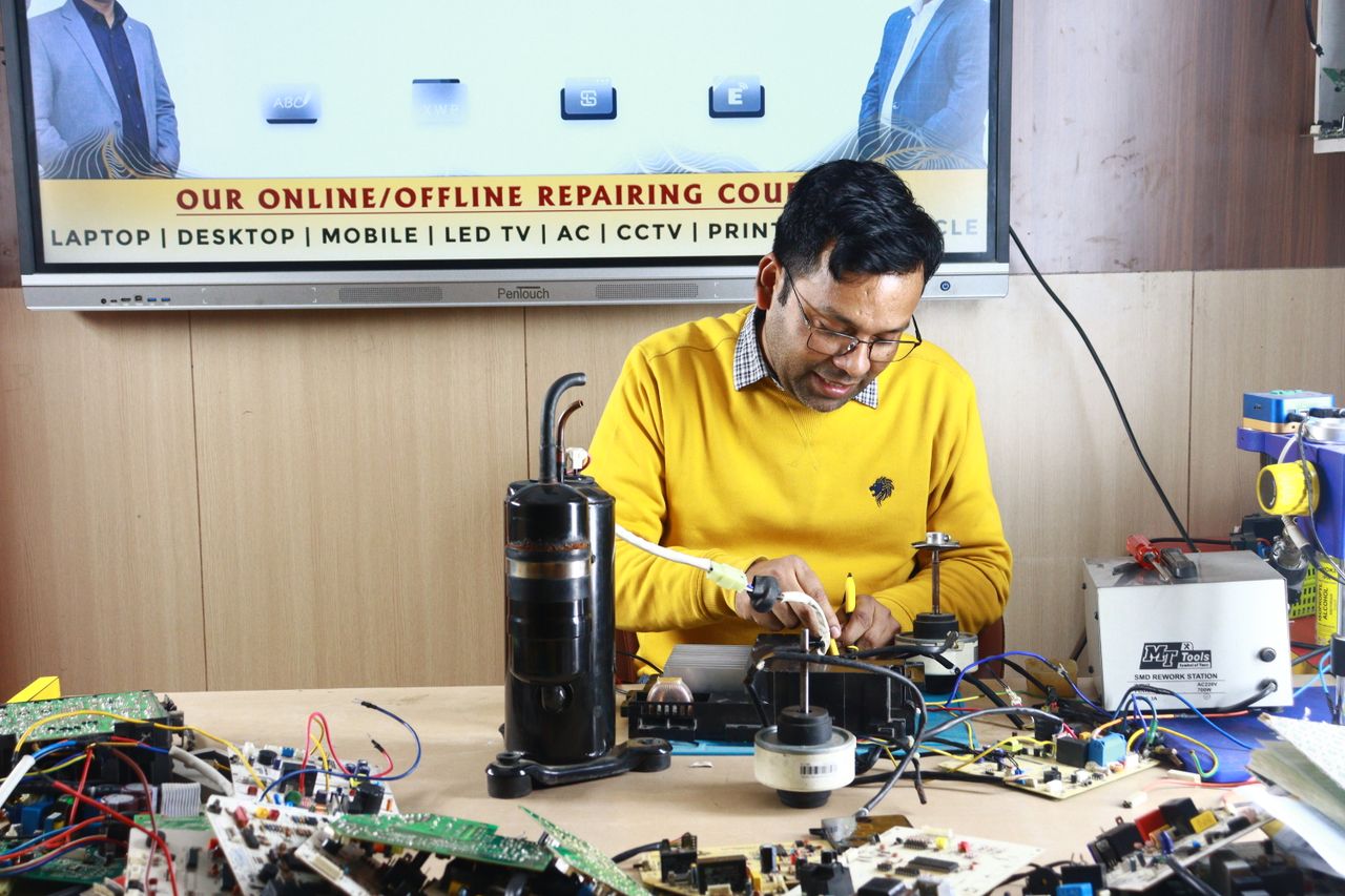 Crafting Captivating Headlines: Your awesome post title goes here Technician engaged in AC repair at a New Delhi workshop. Indoor learning session.
